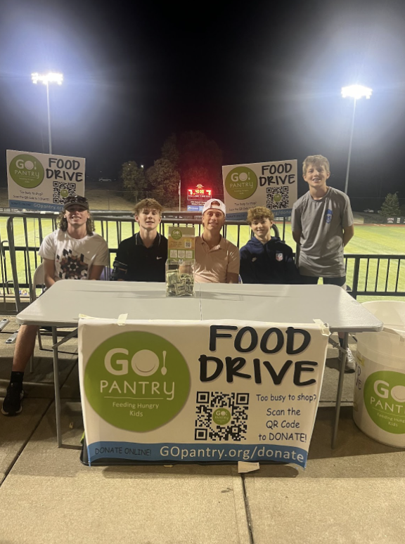 Sam Arnold (12), Isaac Phillips (11), Harrison Gamble (12), Hudson Hargis (9), and Willem Foubert (9), collect donations at the entrance of a girls' soccer game. 

